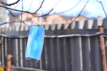A medical mask hangs on a tree branch.