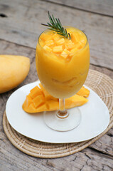 Juicy smoothie from mango in glass mason jar with striped red straw on old wooden background. Healthy life concept, copy space.