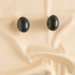 Luxury Easter composition with black eggs on a golden satin background. Minimal luxury Easter concept. Flat lay.