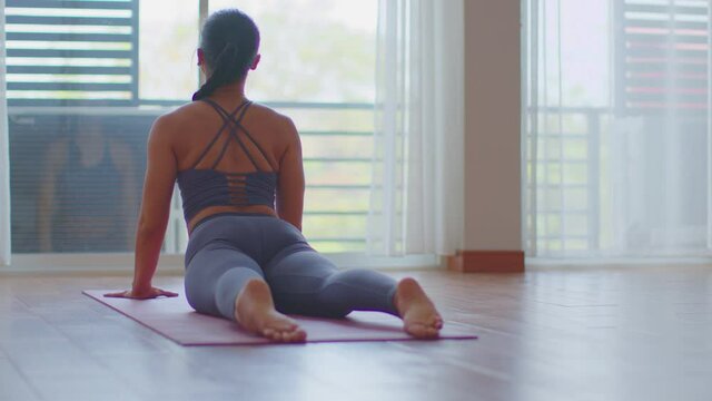 Back of views Calm of Athletic Healthy Asian woman in sportswear workout yoga cobra pose excercise on yoga mat at home in bedroom,wellness healthy lifestyle concept