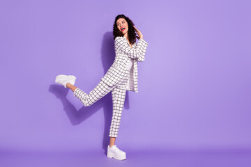 Full length body size portrait if funky woman in suit dancing at party isolated on vivid violet...