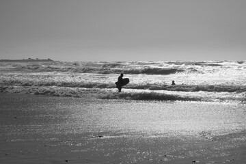 Fototapeta na wymiar Family members surfing together, silhouette, in black and white, conceptual photograph 