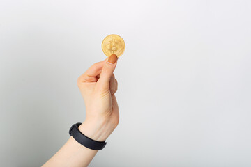 Woman hand is holding a golden bitcoin over white background