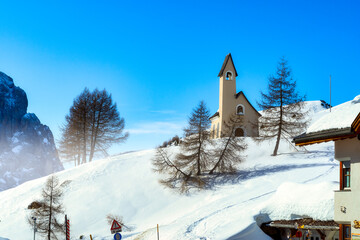 Wolkenstein in Gröden in winter with chapel and view to the pizes de cir, Dolomite, Italy