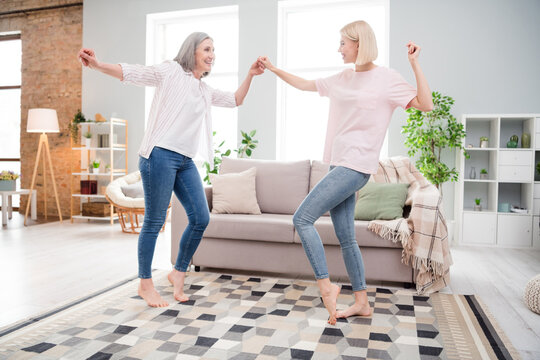 Full body profile side photo of funky mom and daughter smile dance hold hands indoors inside house home