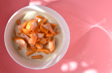 Sweet potatoes cut into pieces to make dessert in a cup with coconut milk. For snacking as a dessert or known as a portion of sweet and savory food. On a pink background