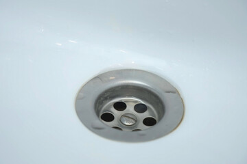 Water is dripping small drops in drain hole of the white sink in bathroom, closeup view. Danger of flooding the apartment.
