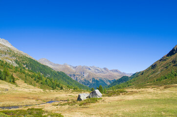 Fototapeta na wymiar mountain valley with stones and meadows above, lush forests below and below rivers and villages