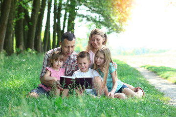 Naklejka na ściany i meble young family reading the Bible in nature