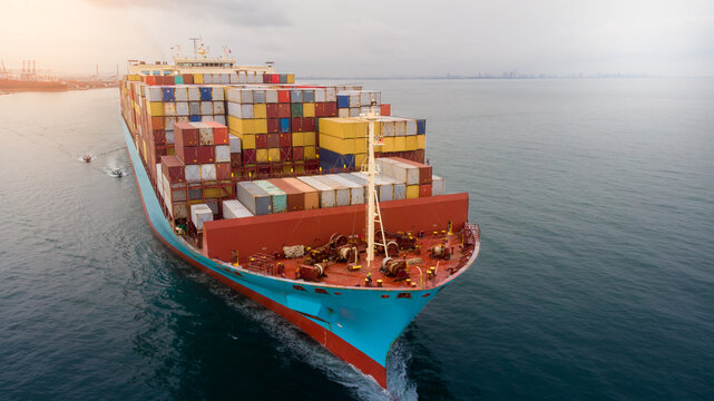 Aerial in front of smart cargo ship carrying container and running near international custom sea port for export cargo.