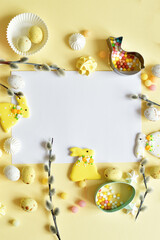Cute homemade sweets with traditional Easter bunny, eggs and springtime decor on yellow bacground.pussy willow branches with catkins. Happy easter concept.Easter holiday greeting card.