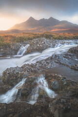 Dramatic, atmospheric landscape of golden sunset or sunrise light over Sligachan River and Black Cuillin mountains on the Isle of Skye, Scottish Highlands, Scotland.