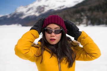 Fototapeta na wymiar winter holidays - young happy and attractive Asian Chinese woman enjoying playful on snow at beautiful Swiss Alps landscape during Christmas vacation trip 