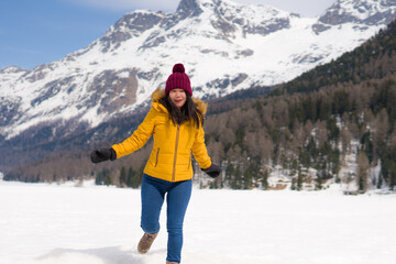 Fototapeta na wymiar winter holidays - young happy and attractive Asian Korean woman enjoying playful on snow at beautiful Swiss Alps landscape during Christmas vacation trip 
