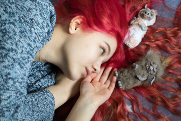 A pink-haired girl in a blue sweater, on hair are toys handmade goblins