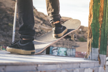 Close up view of teen's feet on a skateboard ready to start a ride over the half pipe. Skater starting jumps and tricks at the skate park. Let's go enjoying. Youth, future brave, danger, risk concept © Fabio Principe