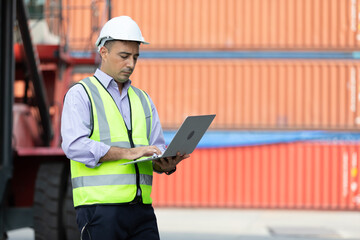 factory workers or engineers using laptop computer for work in containers warehouse storage