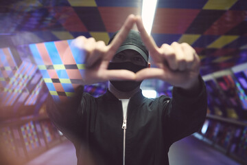 person making triangle hand sign with light flares