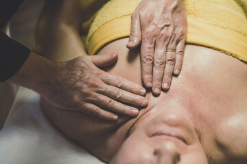 Soft focus view of man massaging a woman in a wellness center Oiled hands on a body relaxing the muscles and relieve tension  .Holistic exercise for calm and clear your mind. Health well-being concept