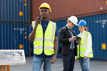 African factory worker or engineer using walkie talkie for preparing a job in containers warehouse storage