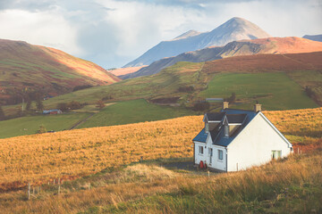 A lone traditional Scottish Highlands white croft house cottage in a rural mountain landscape countryside with Glamaig Peak and the Red Cuillins on the Isle of Skye, Scotland. - obrazy, fototapety, plakaty