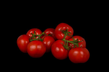 Nine ripe tomatoes on branches on a black background.