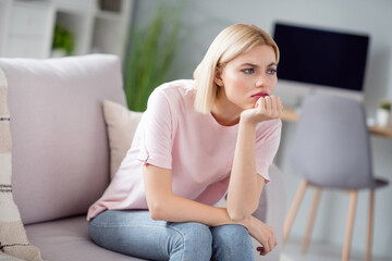 Photo of sad unhappy displeased young woman sit couch bad mood look away sit sofa indoors inside...