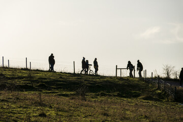 Silhouette of  people walking with child on bike in country park on cold day