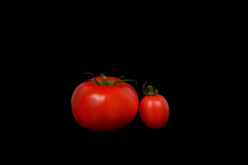 Big tomato and cherry tomato on a black background