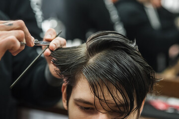 Fototapeta premium Hipster client man visiting in barber shop shaving hair. Modern guy having his hair cut in barbershop.