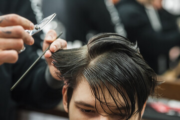 Fototapeta premium Hipster client man visiting in barber shop shaving hair. Modern guy having his hair cut in barbershop.