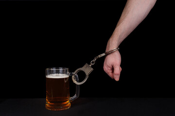 Hand shackled to a beer mug on a black background.