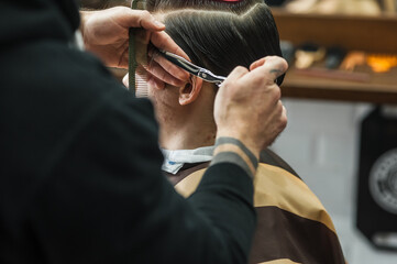 A man in a barbershop.Modern guy having his hair cut in barbershop