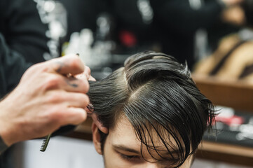 Obraz premium A man in a barbershop.Modern guy having his hair cut in barbershop