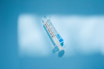 Injection syringe on a blue background. Health care essential equipment for injections.