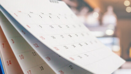 Close up white paper desk calendar with blurred bokeh background appointment and business meeting...