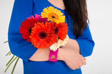 Close up image of a young woman with a bouquet of beautiful colorful flowers in her hands. Girl in a blue dress holding a bouquet of bright summer flowers
