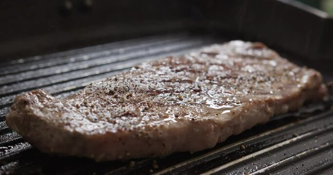 Sprinkle black pepper and salt on the Grilling Beef steak on a hot pan, Ingredients for cooking, Front view food concept.