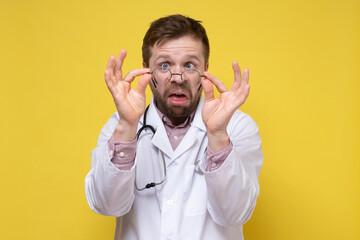 Bizarre doctor with poor eyesight has taken off glasses and is looking, with a stupid expression on...