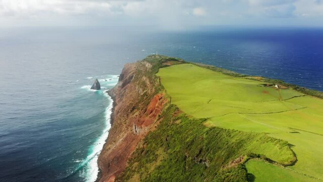 Lighthouse of Ponta dos Rosais, Sao Jorge, Azores, Portugal. Beautiful vacation spot with lighthouse. Drone footage of the island with indented coastline with an oblong shape. High quality 4k footage