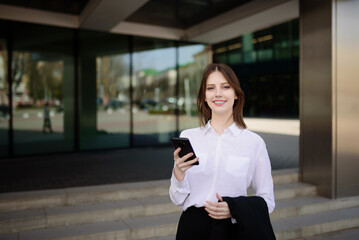 Fototapeta premium Young beautiful smiling girl replies to a message on her mobile phone