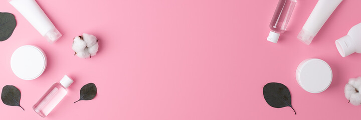 Cosmetic background with skin care products and flowers on pink. Flat lay, copy space