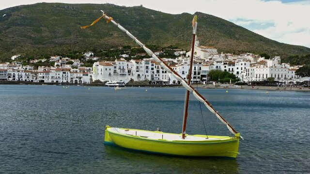Seascape of the "COSTA BRAVA" in Catalonia, Spain.
Ancient boat fishing with lateen sail anchored in front of tourist coast village of "CADAQUES".Time lapse.
