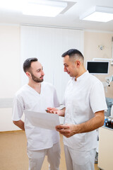 Obraz premium A dentist's hand holds an x-ray image and talks to a colleague doctor about medications and surgical treatments.