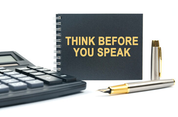 On a white background, there is a calculator, a pen and a black notebook with the inscription - THINK BEFORE YOU SPEAK