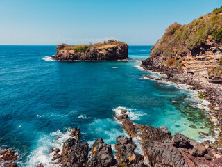 Fototapeta premium Blue transparent ocean with coastline and island. Aerial view.