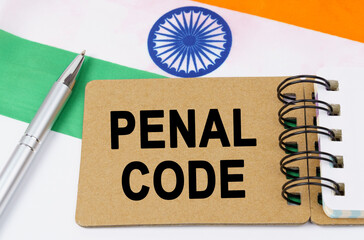 Against the background of the flag of India lies a notebook with the inscription -PENAL CODE