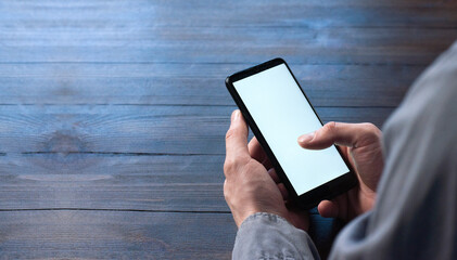 Phone in hand. Phone with white and blank screen. On a wooden table. Businessman