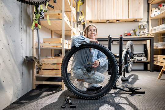 Portrait of a young handywoman reparing her bicycle in the beautiful small workshop at home. DIY concept