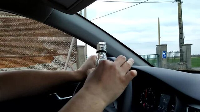 personne qui conduit avec une bouteille d'alcool dans les mains